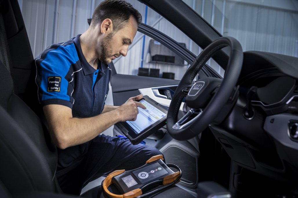 Ein TÜV NORD Mitarbeiter verwendet ein Tablet zur Fahrzeugdiagnose im Innenraum eines Autos