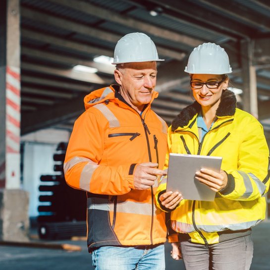 Arbeiter in Schutzanzügen und Helmen überprüfen das Inventar eines Warenlagers