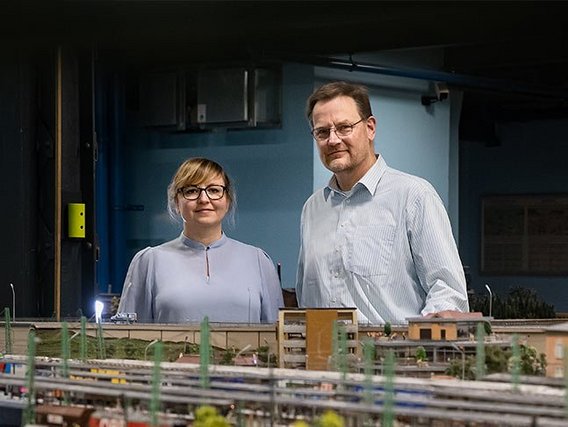 A man and woman stand behind a detailed model railway exhibit