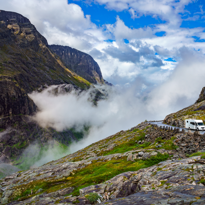 A white camper van drives along a winding mountain road