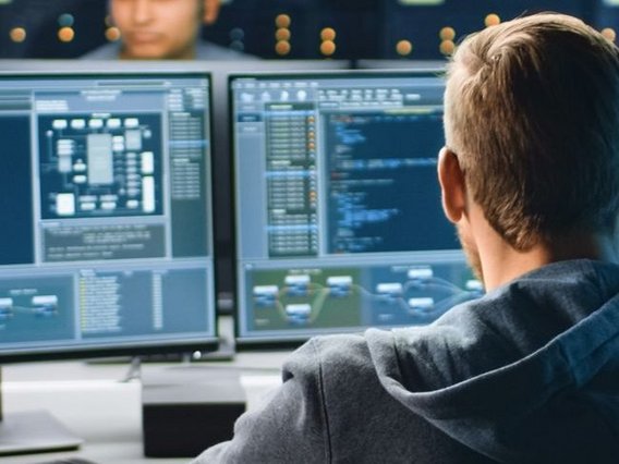 A man sits in front of two computer screens