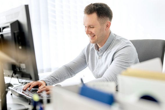 A man sits at a desk and types on his computer.
