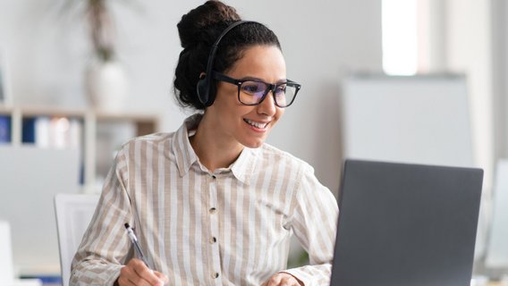Frau mit Headset arbeitet am Laptop im Büro