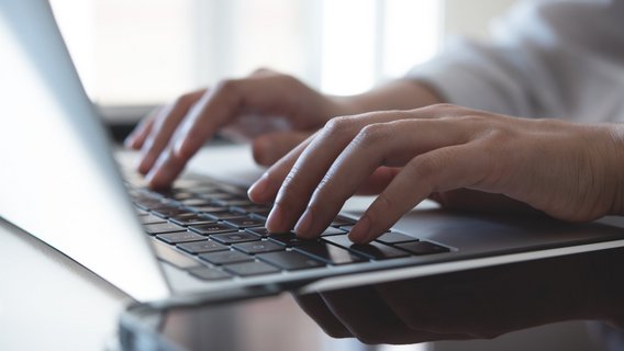 Hände tippen auf Laptop-Tastatur