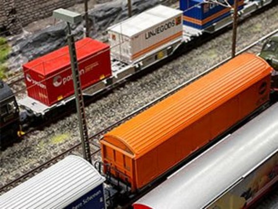 A detailed model railway with colorful freight trains, containers, and realistic infrastructure