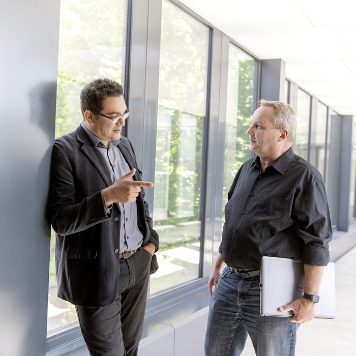 Two men talking to eachother in a hallway.