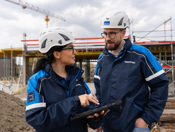 Zwei Ingenieur:innen vor einem Bauprojekt.