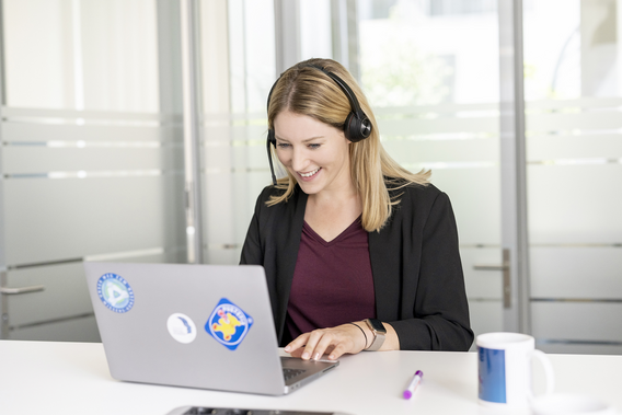 Eine Frau mit Headset am Laptop