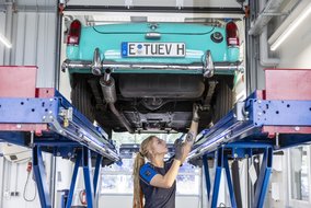 Oldtimer auf Hebebühne in der Werkstatt, Unterseite wird inspiziert.