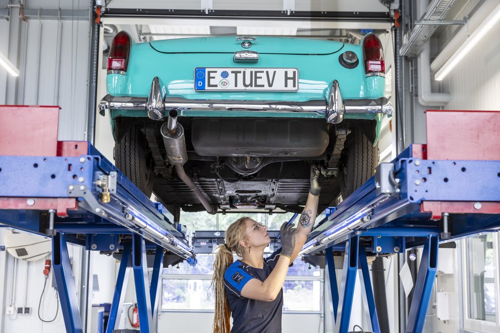 Oldtimer auf Hebebühne in der Werkstatt, Unterseite wird inspiziert.